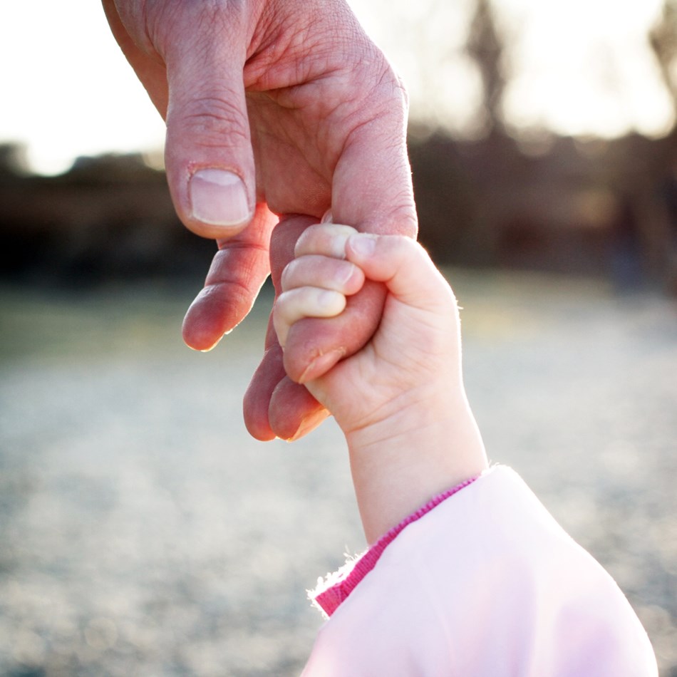 Et barns hånd tager fat om en ældre persons finger