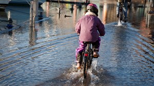 Barn cykler gennem oversvømmet havneområde