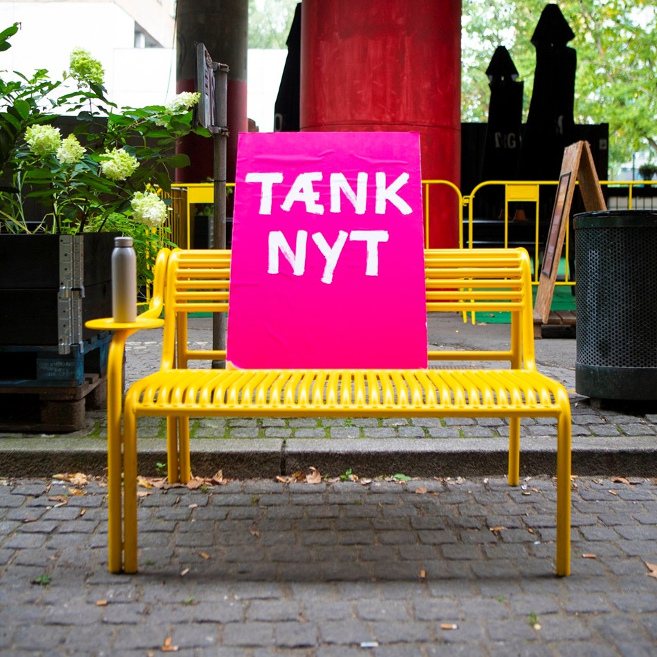 Tænk nyt-plakaten slapper af på en gul bænk