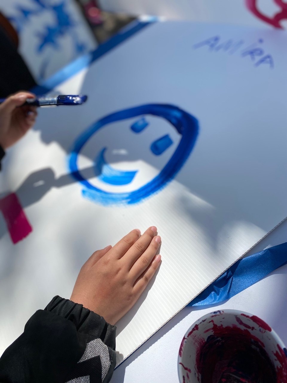 Børnehænder maler et smilende ansigt på en valgplakat