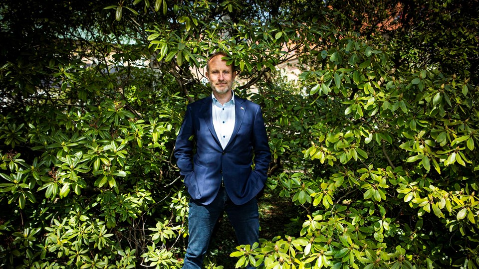 Martin Lidegaard står midt i en stor, grøn busk som fylder hele billedet